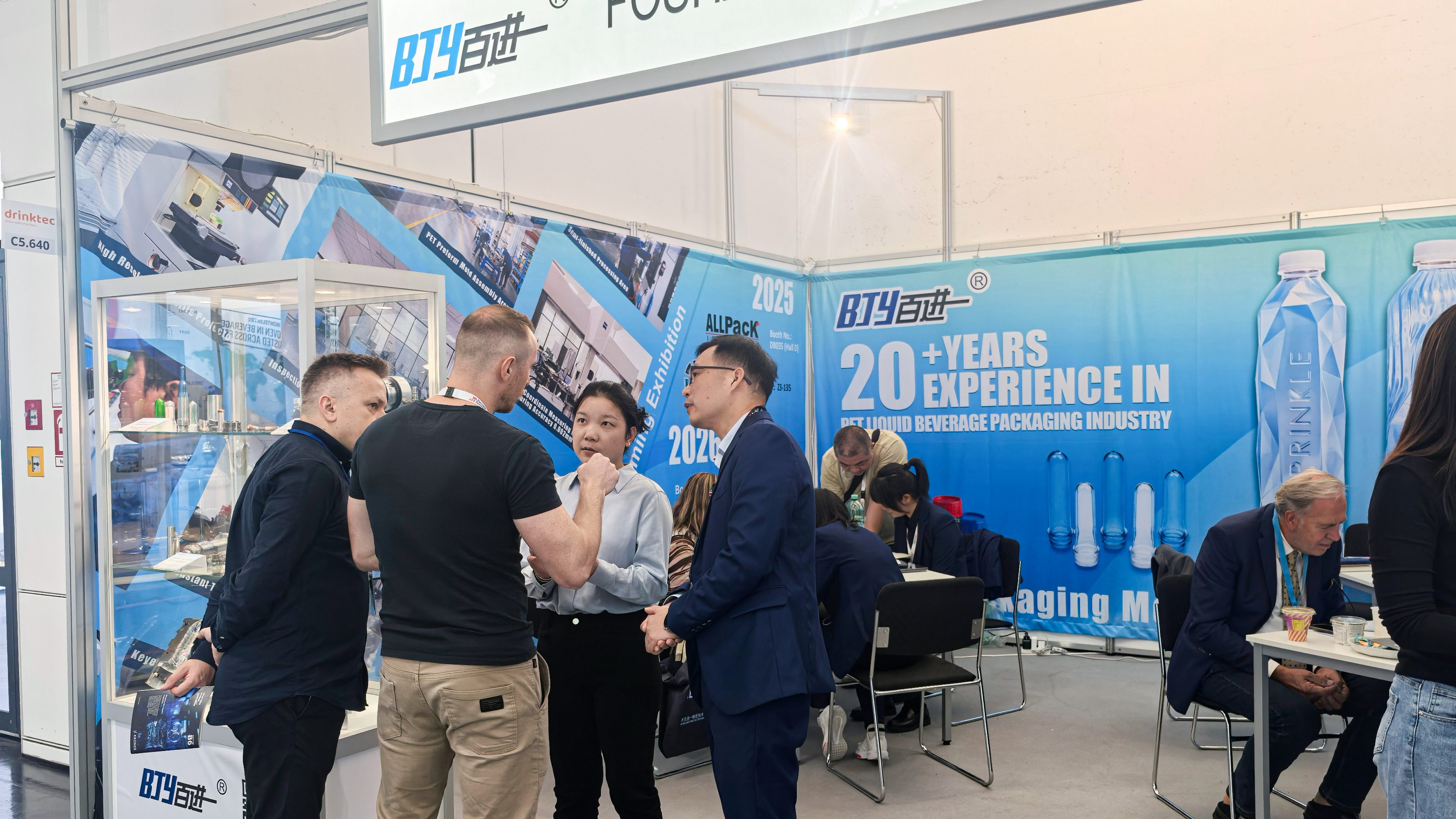 Baijinyi engineers discussing PET injection and blow molds with clients at drinktec 2025 booth C5-640, Munich.